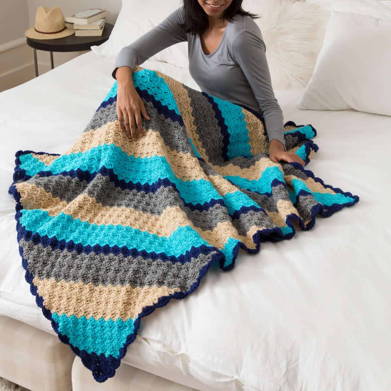 woman laying under the striped corner to corner throw