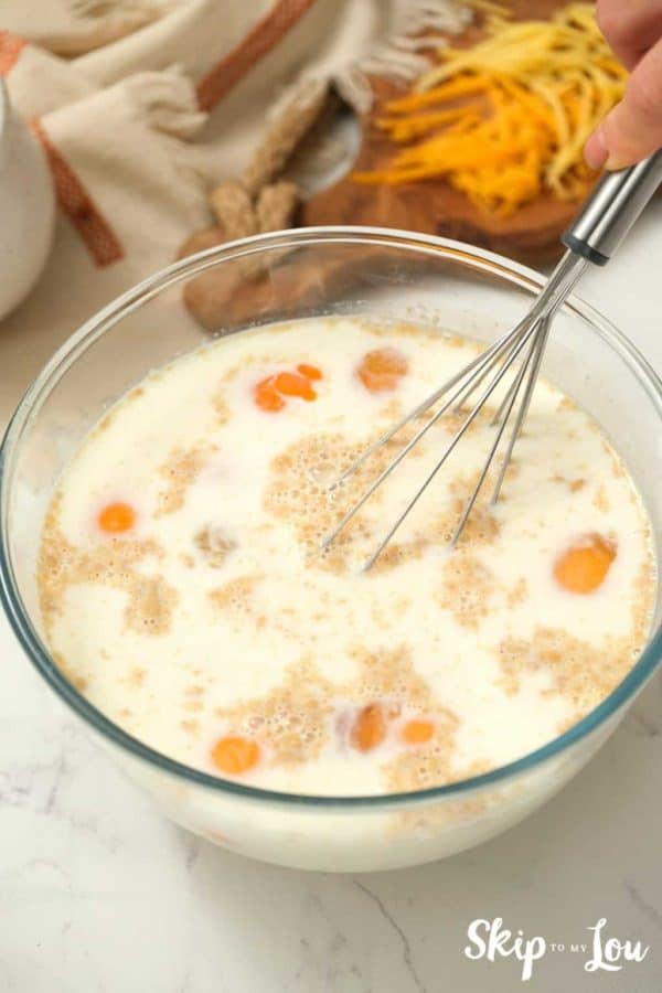 wet ingredients with whisk in a mixing bowl for egg strata from Skip to My Lou recipe