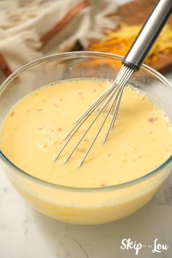 egg mixture with whisk in a mixing bowl for egg strata from Skip to My Lou recipe
