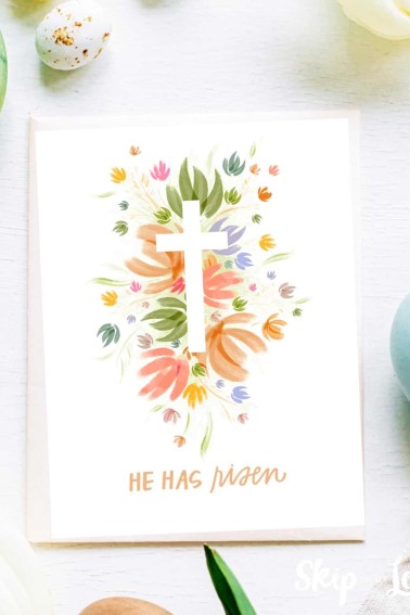 Image shows a Happy Easter he has risen greeting card with a colorful cross in the middle and surrounded by Easter decoration.