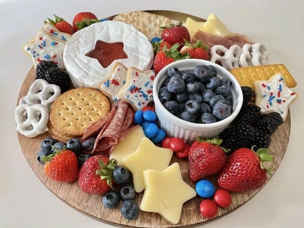better homes & gardens made a simple board with brie, blueberries, strawberries, and more. 