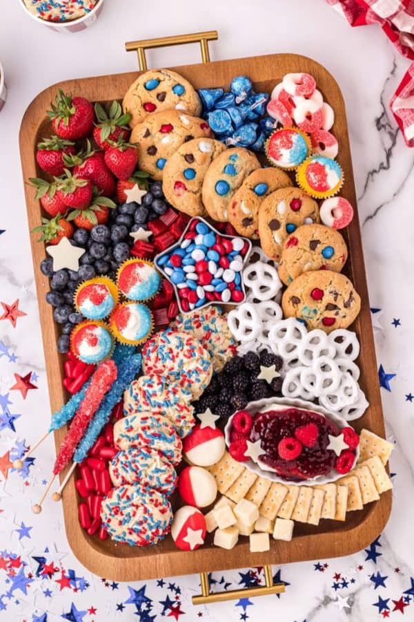 a dessert 4th of july charcuterie board idea that anyone would eat. It includes cookies, pretzels, fruit, and cupcakes from crazy for crust. 
