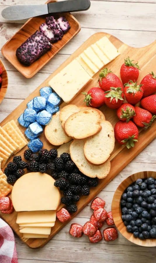 a date night 4th of july charcuterie board idea with bread, berries, and red and blue dove chocolates.