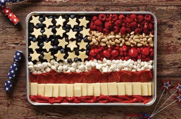 a charcuterie board in the form of a flag from hy-vee with star shaped cheese, blueberries, and raspberries is one of the simplest 4th of july. charcuterie board ideas.  