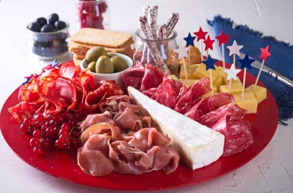 In the kitch created a charcuterie board full of meat, cheese cubes and other add ons.