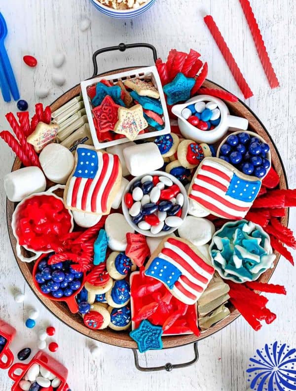 starting off the 4th of july charcuterie board ideas is a candy and treat filled board from mom on timeout with cookies, m&ms, gumballs, and more.