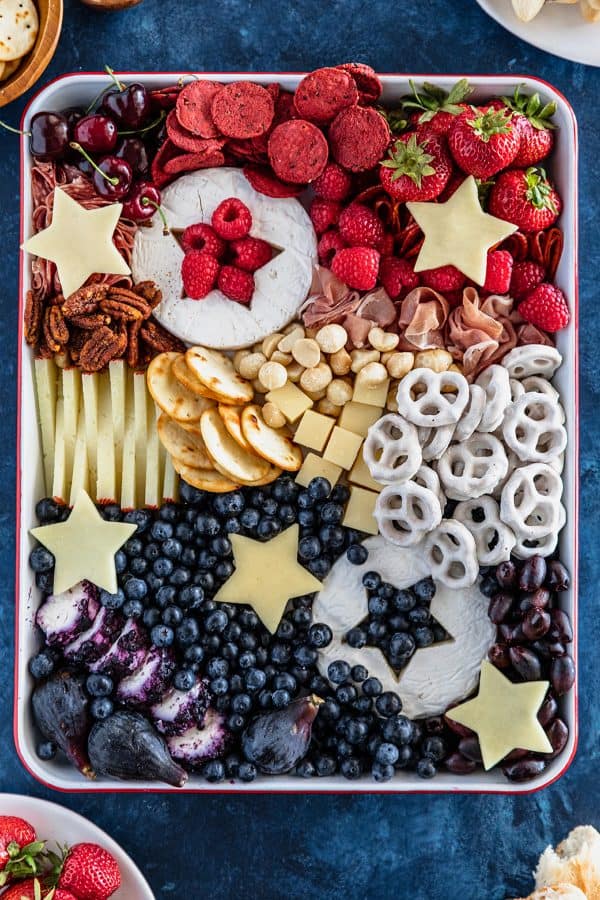 two blocks of brie become patriotic when beautiful stars are cut from them and filled with blueberries and raspberries. Surrounded by cheese, meat, and more from number 2 pencil.