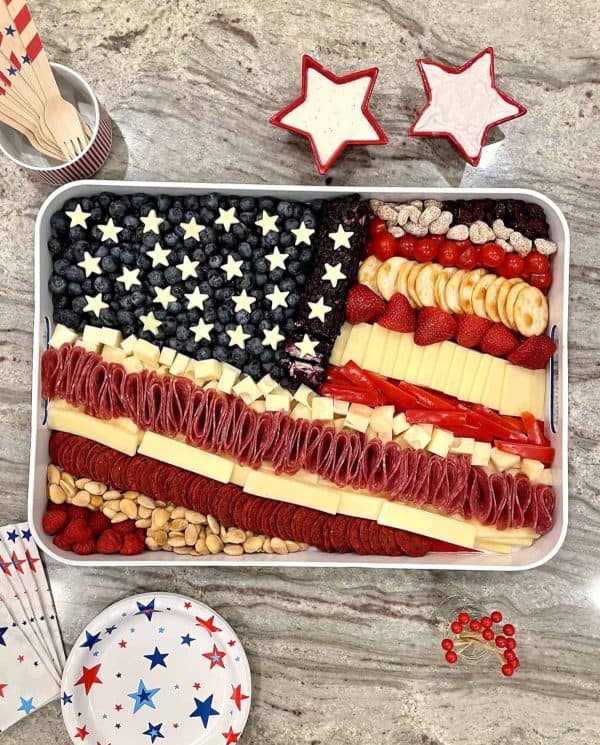 An American flag from the baker mama includes a variety of cheeses, fruits, candies, and more. 