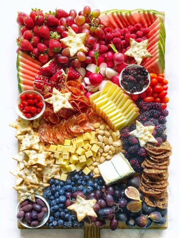 a fully packed board from the delicious life. It include watermelon, apples, strawberries, crackers, nuts, and so much more. 