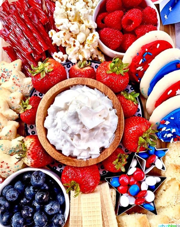 a snack board with cookie butters filled with m&ms, homemade sweet dip, cookies, popcorn, and more from urban bliss life.