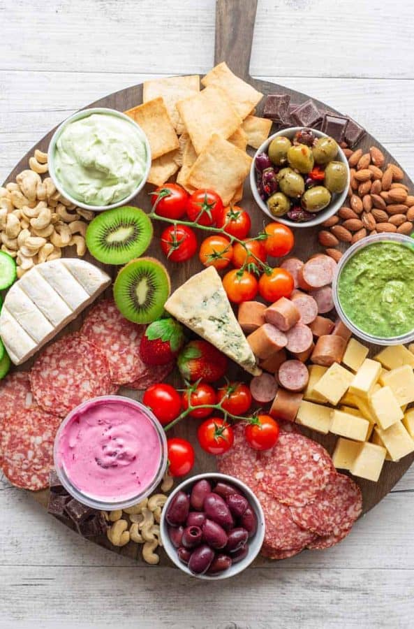 a large board from the big mans world with fruit, dip, veggies, meat, and cheese