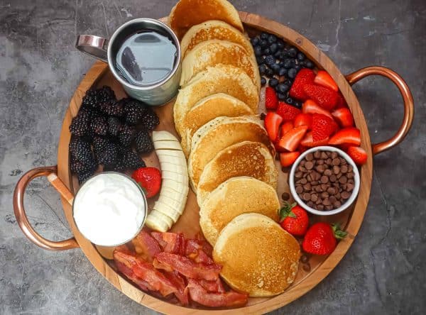 a round board full of pancakes, toppings, and bacon from tasty oven.
