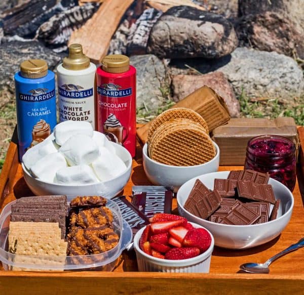 three bottles of sauces and bowls full of toppings for the perfect s'more from Bake it with love