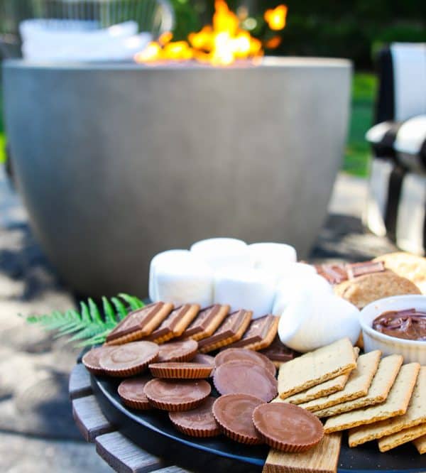 A board next to the fire with marshmallows, chocolate, and cookies from Modern Glam.