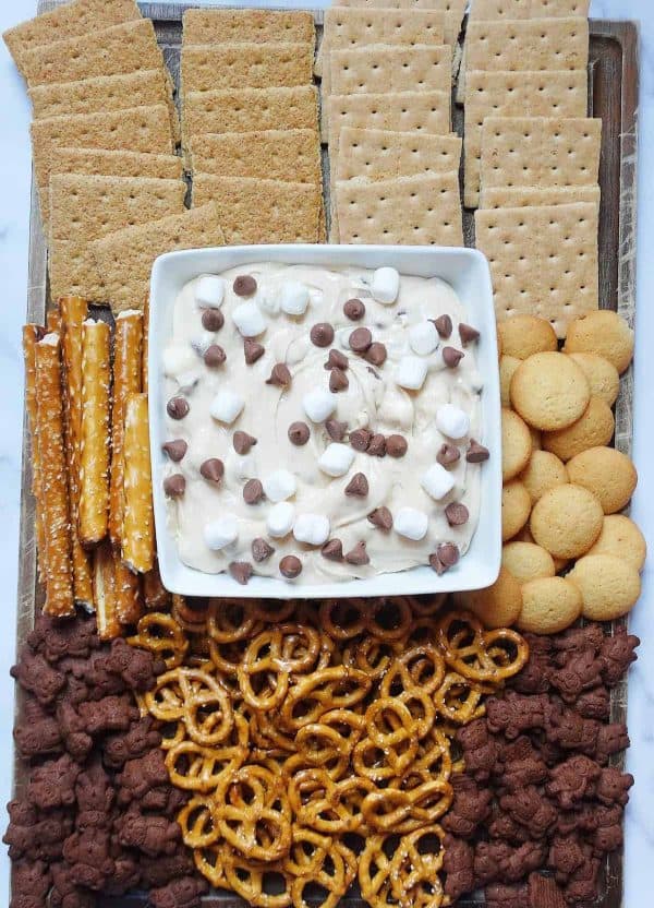 a chocolate, s'mores cookie dough dip takes the center of the board with cookies and crackers surrounding it from My Mini Chefs