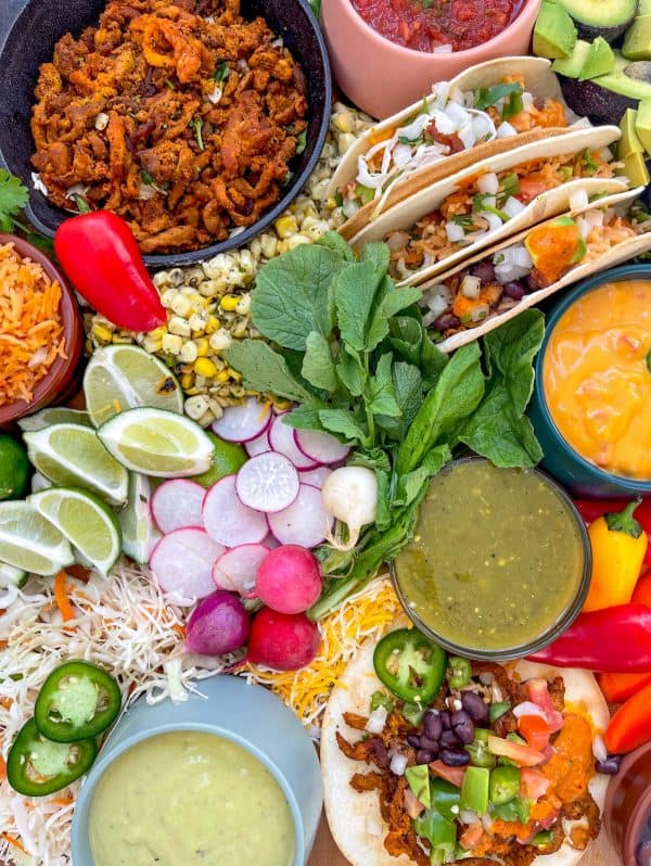 A large colorful taco charcuterie board with plenty of dips and toppings from Azteca foods.