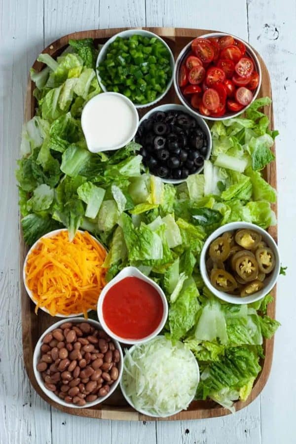 A dorito taco salad board with lettuce, tomatoes, olives, cheese, and more from Medwexican.
