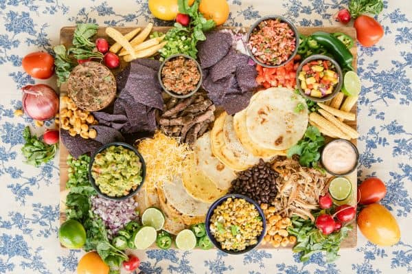 Another taco charcuterie board idea that gives the option of chips or soft shell. A bunch of little bowls with salsas, beans, corn, etc.