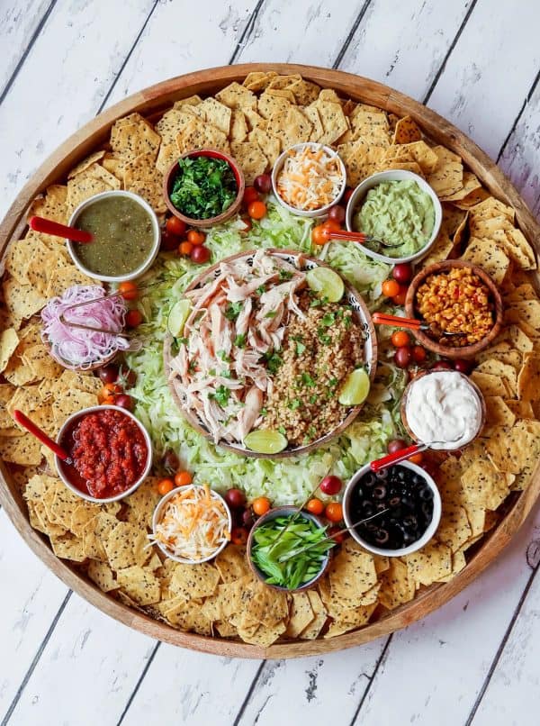 a large nacho charcuterie board from  the reluctant entertainer with chicken, rice, lettuce, and other tac fillings. 