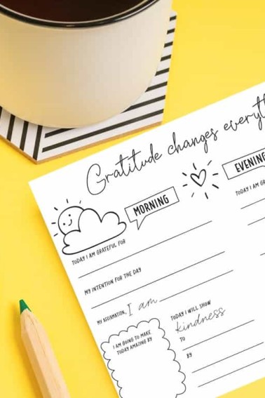 gratitude journal template next to a cup of coffee and a potted plant.