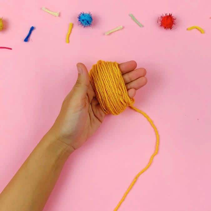 wrapping yarn around hand to make pom pom
