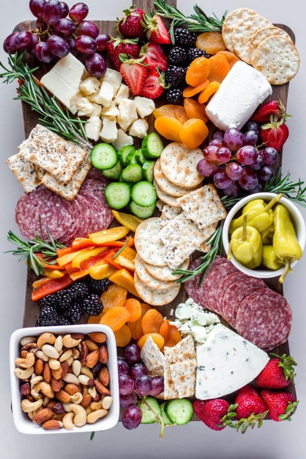 bits and bites has a board with peppers, meats, cheese, fruit, and nuts.