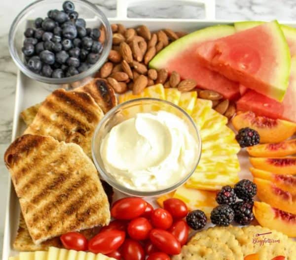 toast, watermelon, pesto, peaches, tomatoes, and more on a tray from blogghetti