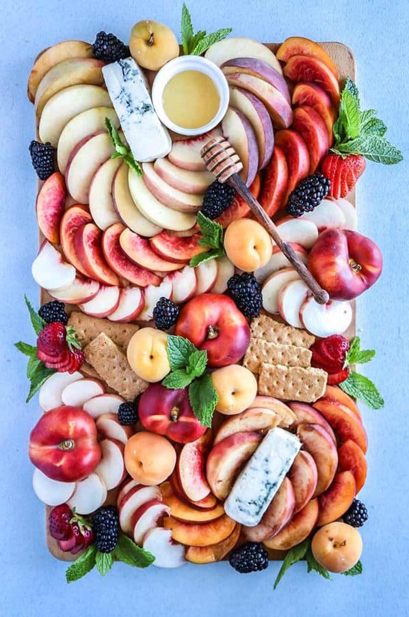 a summer charcuterie board with a variety of peaches, cheese, and dips from fork in the road.