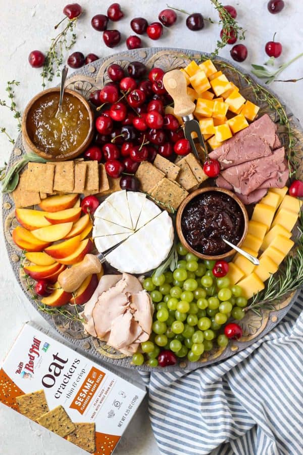 a charcuterie board from pink owl kitchen with cheese, fruit, and meat on a round board.