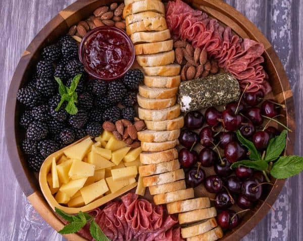 a charcuterie board with meat, cheese, baguette slices, and cherries from smack of flavor