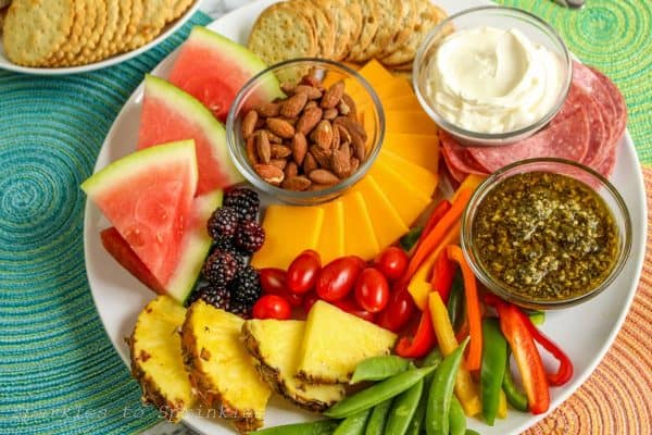 Sparkles to sprinkles has a simple charcuterie board with dips, pineapple, peppers, and crackers with cheese.