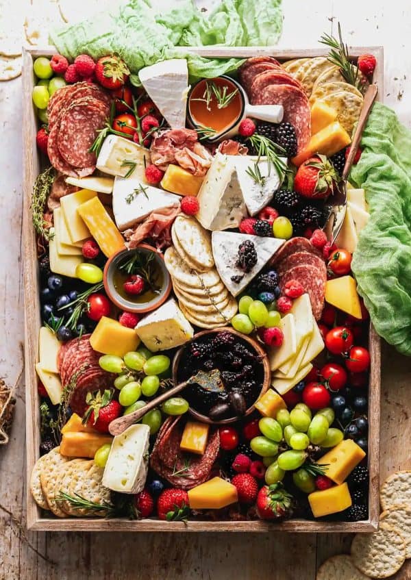 A rectangle tray with cheese, fruit, meat, crackers, and dips from sweet tea and thyme.