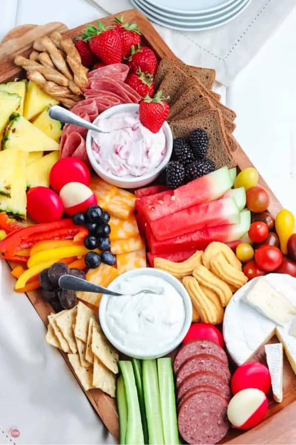 a charcuterie board with fruit, fruit dip, veggies, meat, and other options from take two tapas