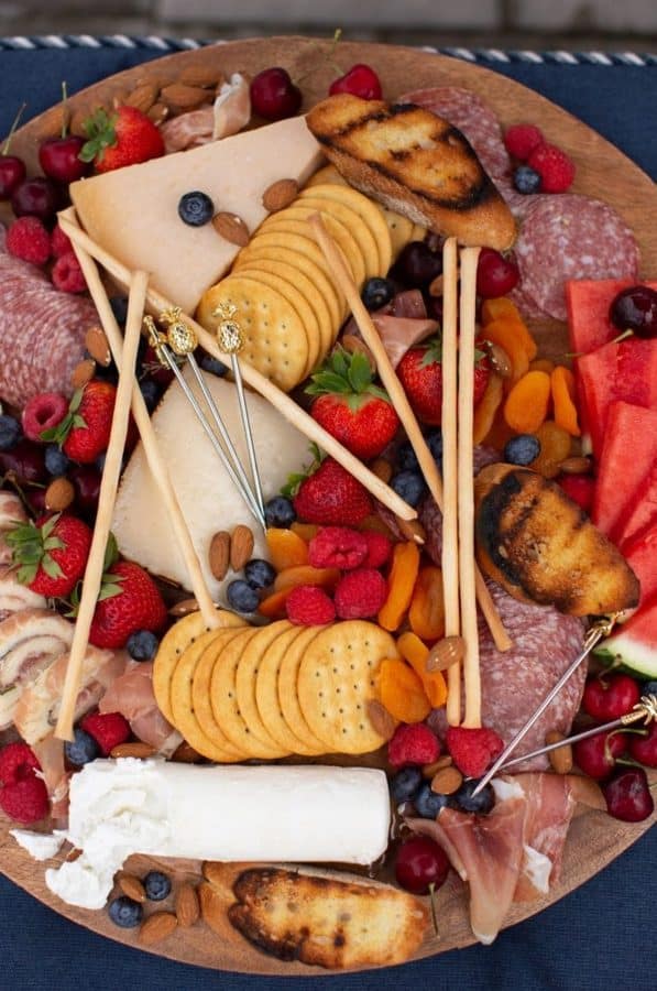 A board with crackers, raspberries, cheese, and more from the suburban soap box.