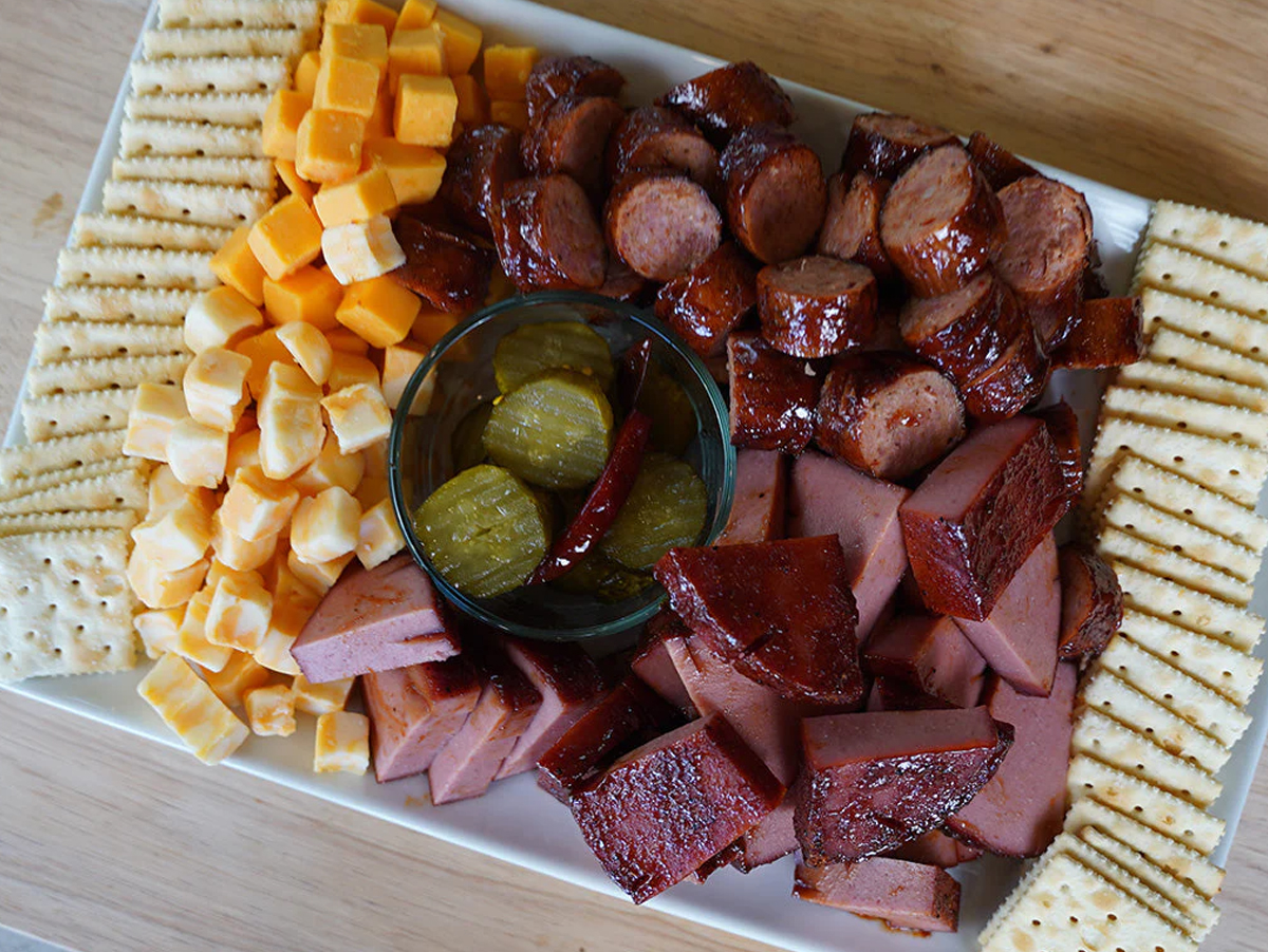 A simple board from heath riles BBQ with grilled sausage, cheese cubes, and crackers