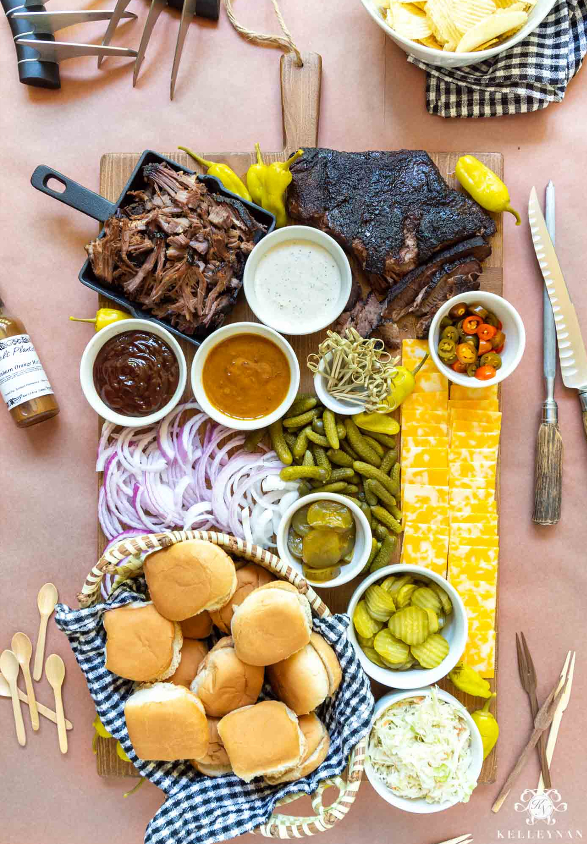 One of the easiest bbq charcuterie board ideas from Kellys Nan's with brisket, pulled pork, dips, and cheese served with a basket of buns.