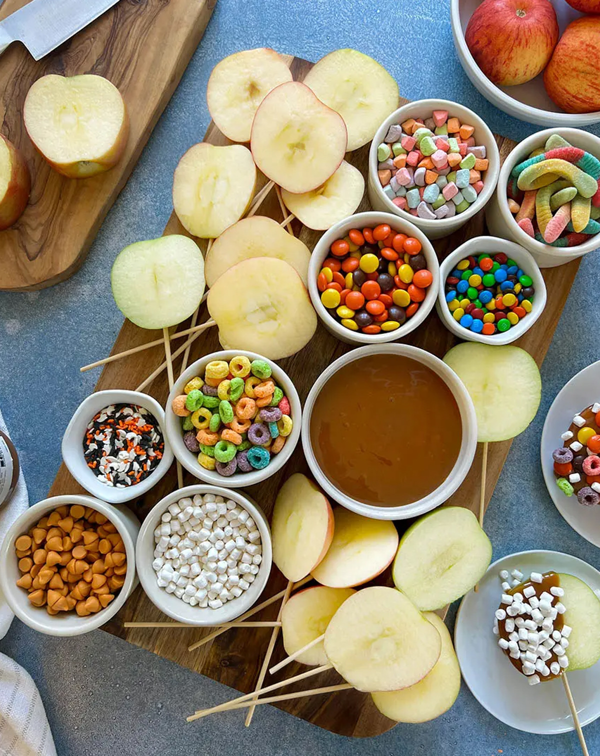 Apples on a stick, caramel sauce, toffee bits, Fruit Loops and sour gummy snakes fill Ain't Too Proud To Meg's Caramel Apple board.