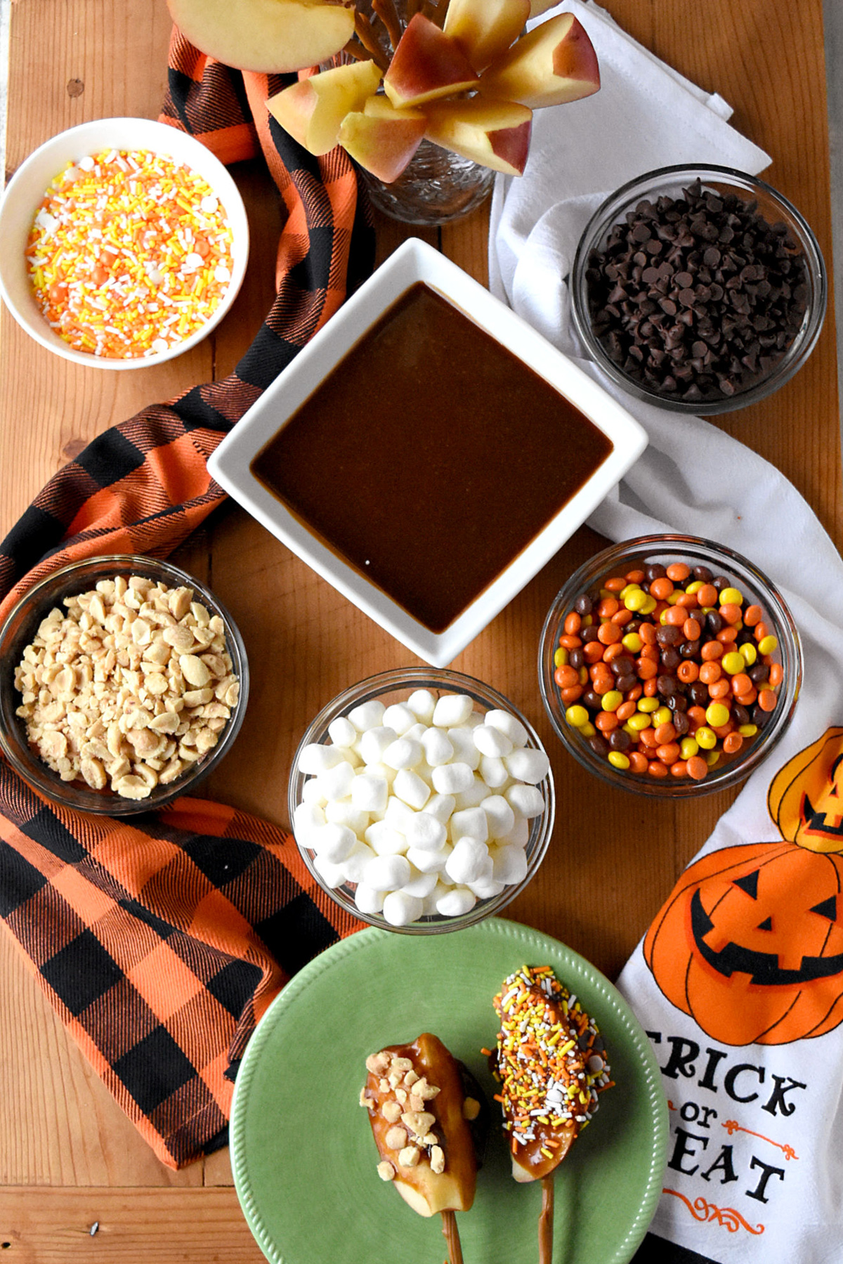 A Kitchen Hoor's Adventures Caramel Apple Board is full of apple slices, chocolate chips, m&m's, sprinkles, and marshmallows.
