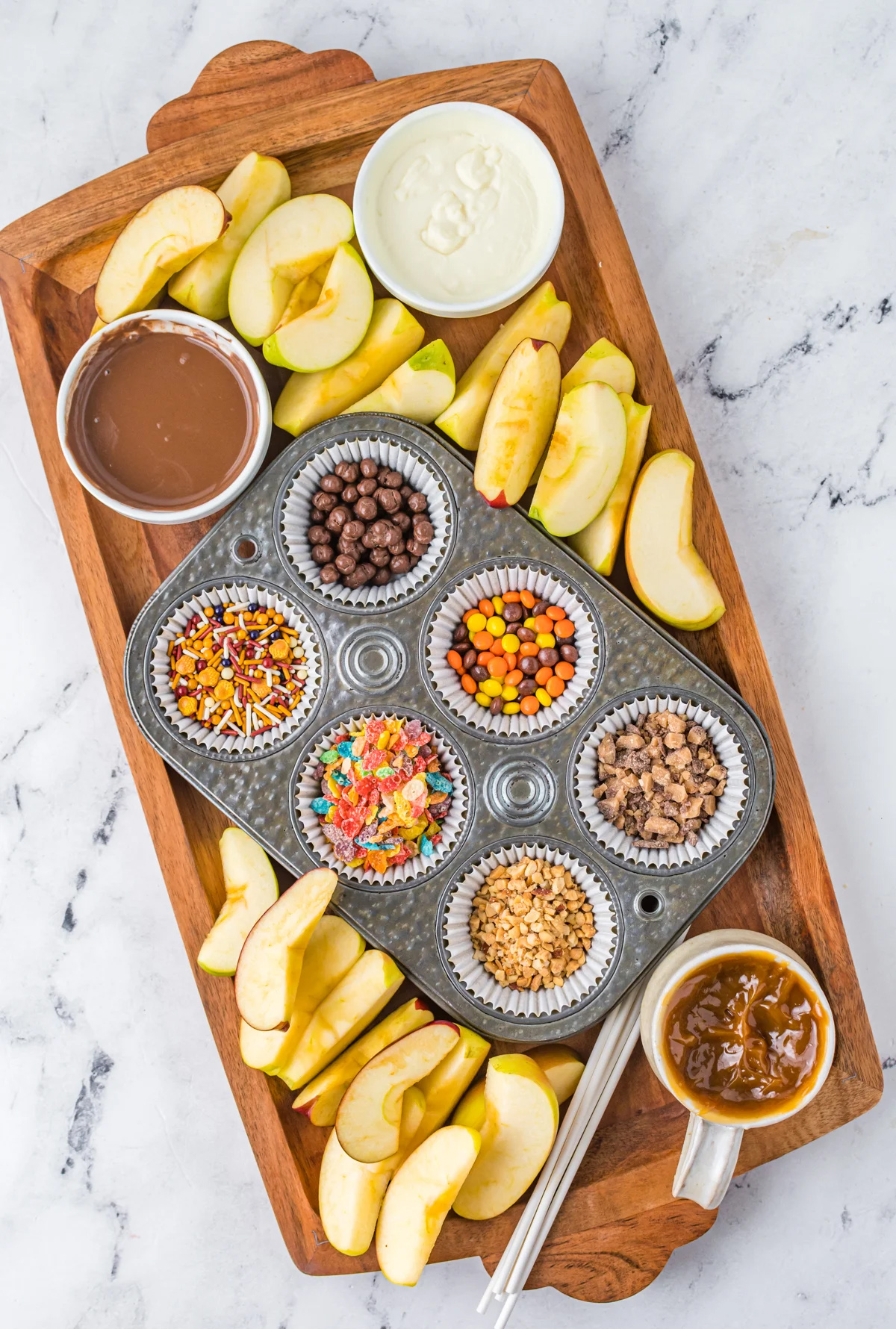 Apple slices, caramel sauce, peanut butter m&m's, nuts, reeces, and sprinkles fills Play Party Plans Fall Caramel Apple Board.