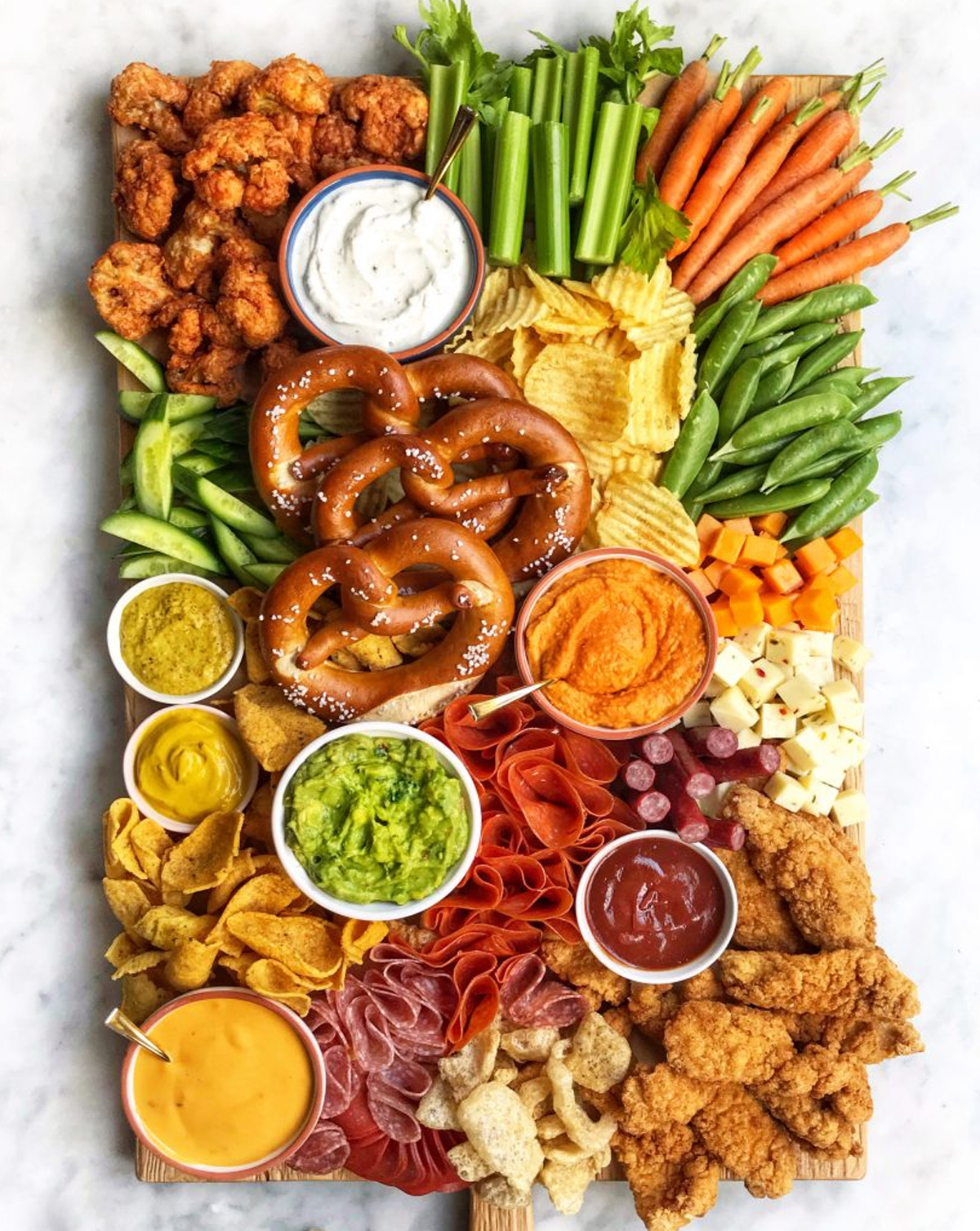 The Delicious Life's football themed board has carrots, celery, pretzels, chips, meats, and cheese.