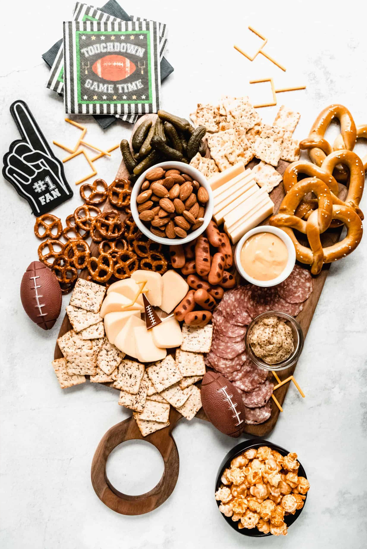 Cheese, pretzels, pickles, meat, almonds, and crackers fill Windy City Dinner Fairy's football themed board.