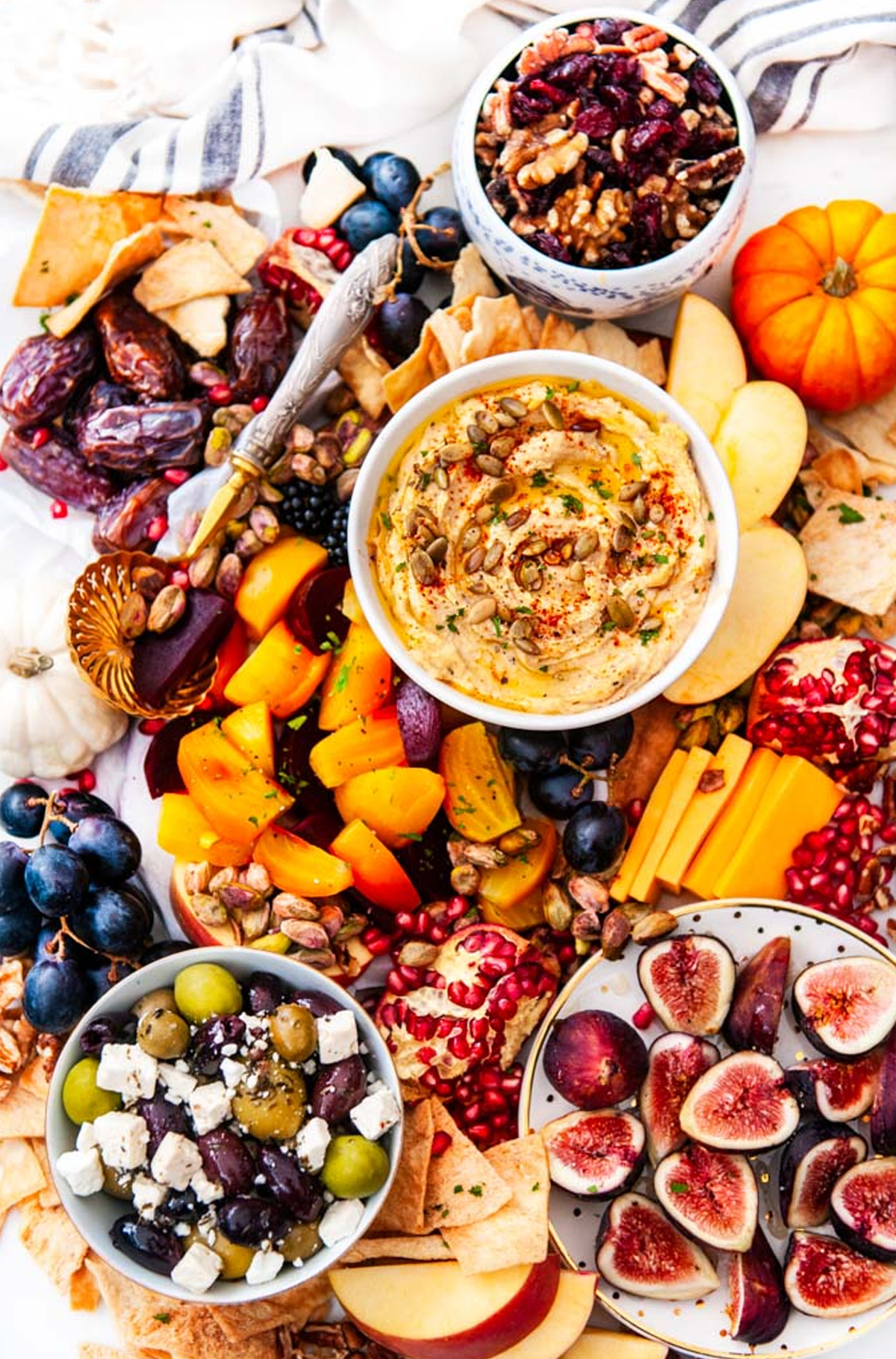 an autumn greek charcuterie board from aberdeen's kitchen with peaches, cranberries, figs, and a roasted fall hummus.