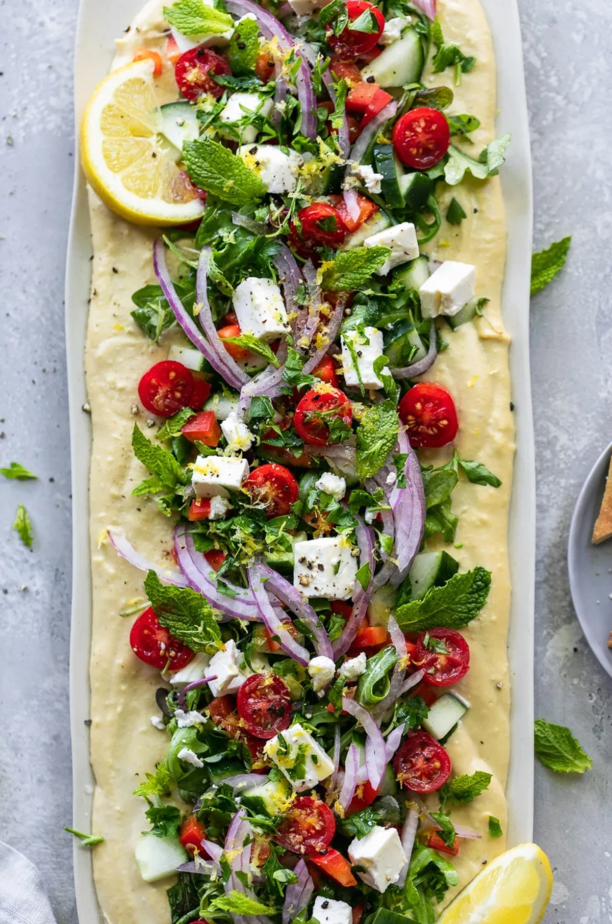 a greek salad board from spices in my DNA with cucumbers, tomatoes, lettuce, onions, and more.