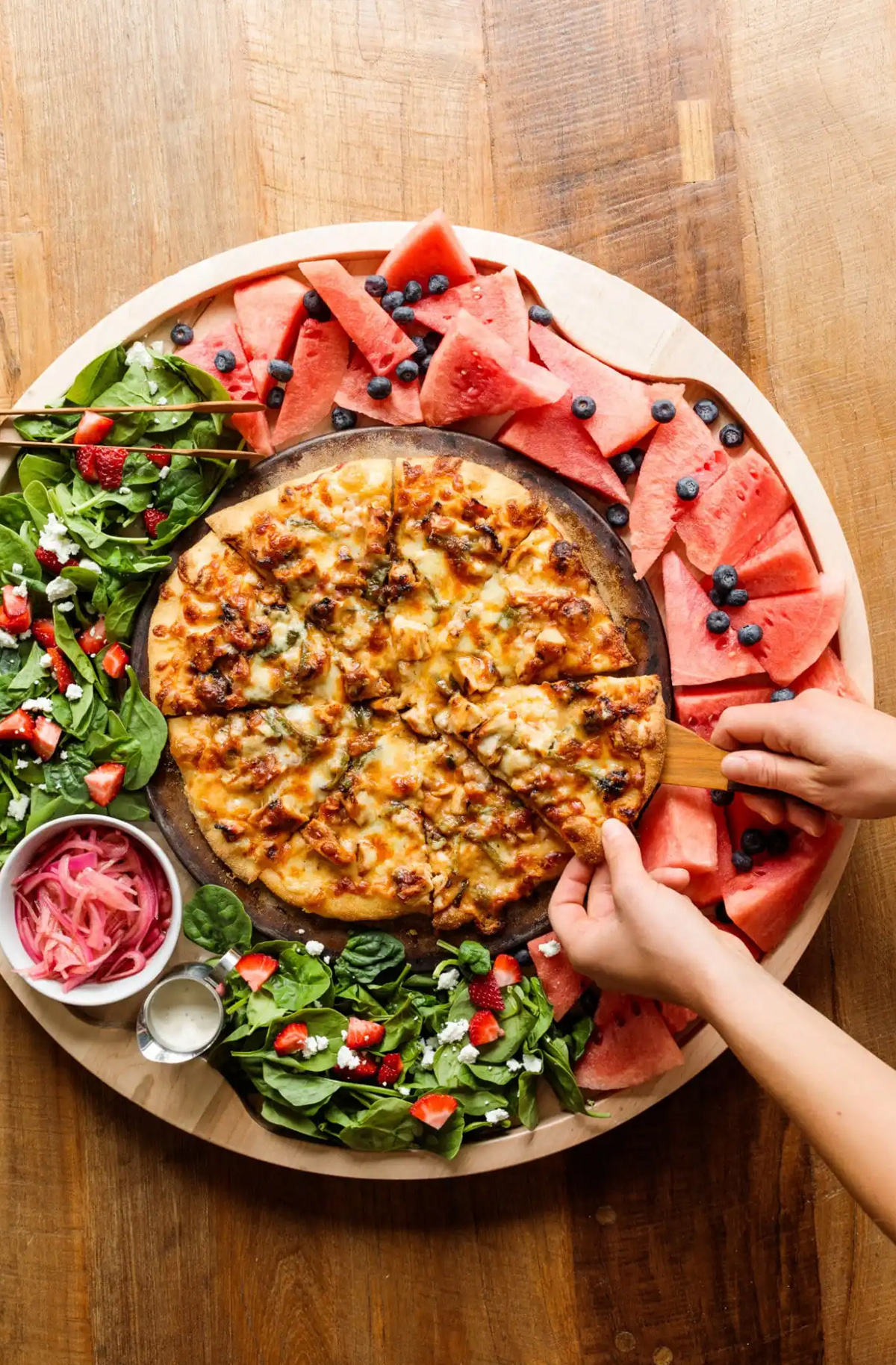 The Reluctant Entertainer's pizza board shows a BBQ Pizza with chicken tenders, red onion, cheese, fruit and salad.