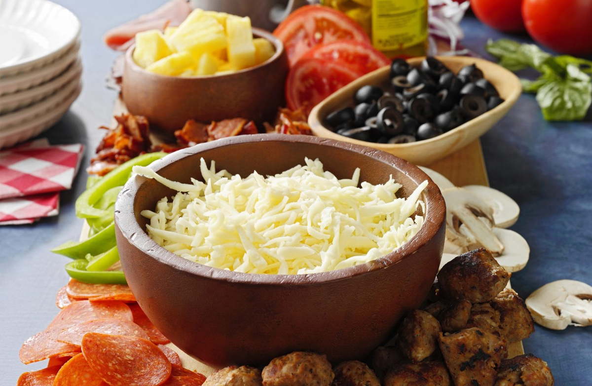 Taste of Home's pizza charcuterie board is showcasing pizza topping like olives, cheese,, tomatoes, and red onions.