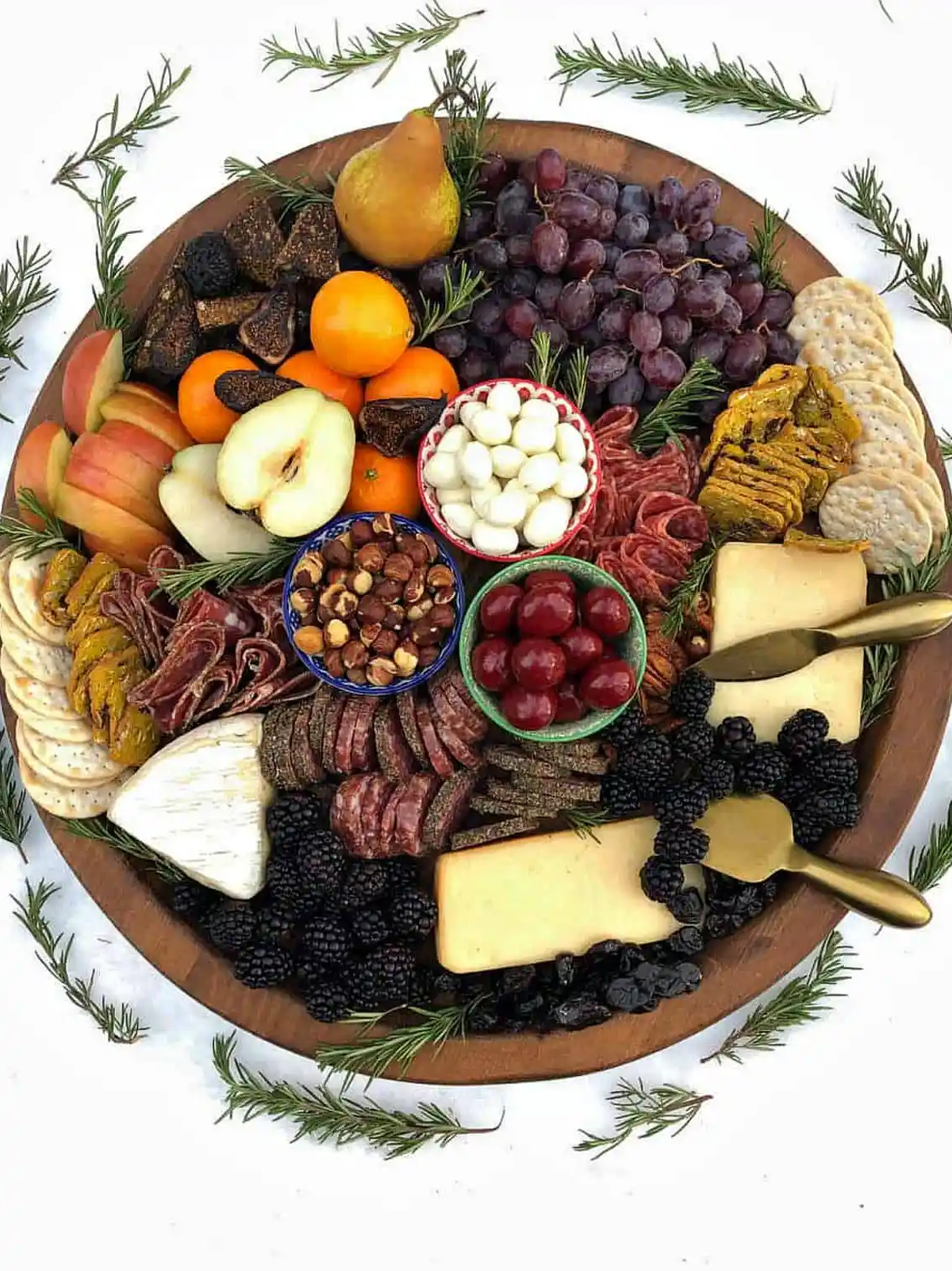 Reluctant Entertainer created a rustic charcuterie board full of cheese, fruits, crackers, and more.