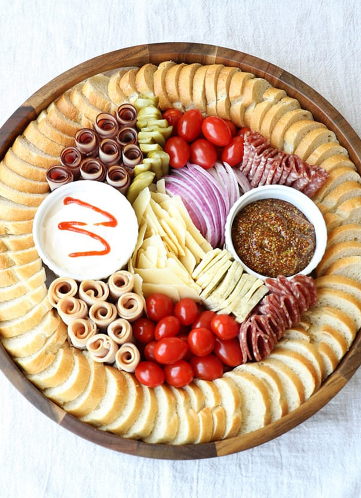 Belly Full's sandwich charcuterie board showcases tomatoes, meats, onions, sauces, cheese, and bread.