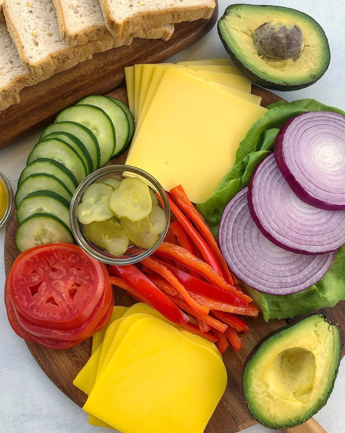 Avocado, onions, cheese, bread, lettuce, pickles, and bread are on The Urben Life's Sandwich Board.
