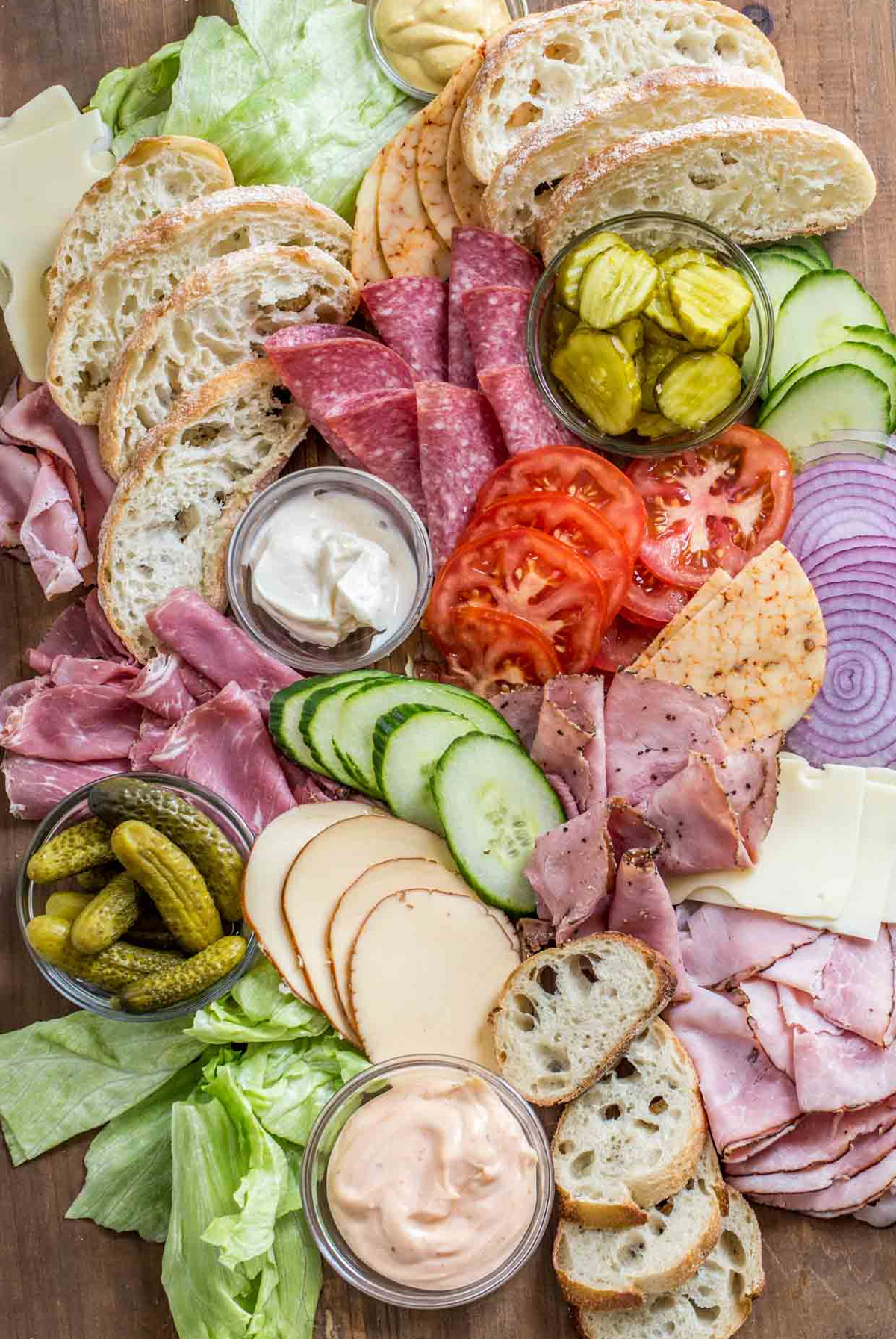 Valentina's Corner sandwich board includes pickles, a variety of deli meat, tomatoes, cheese, lettuce, and bread.