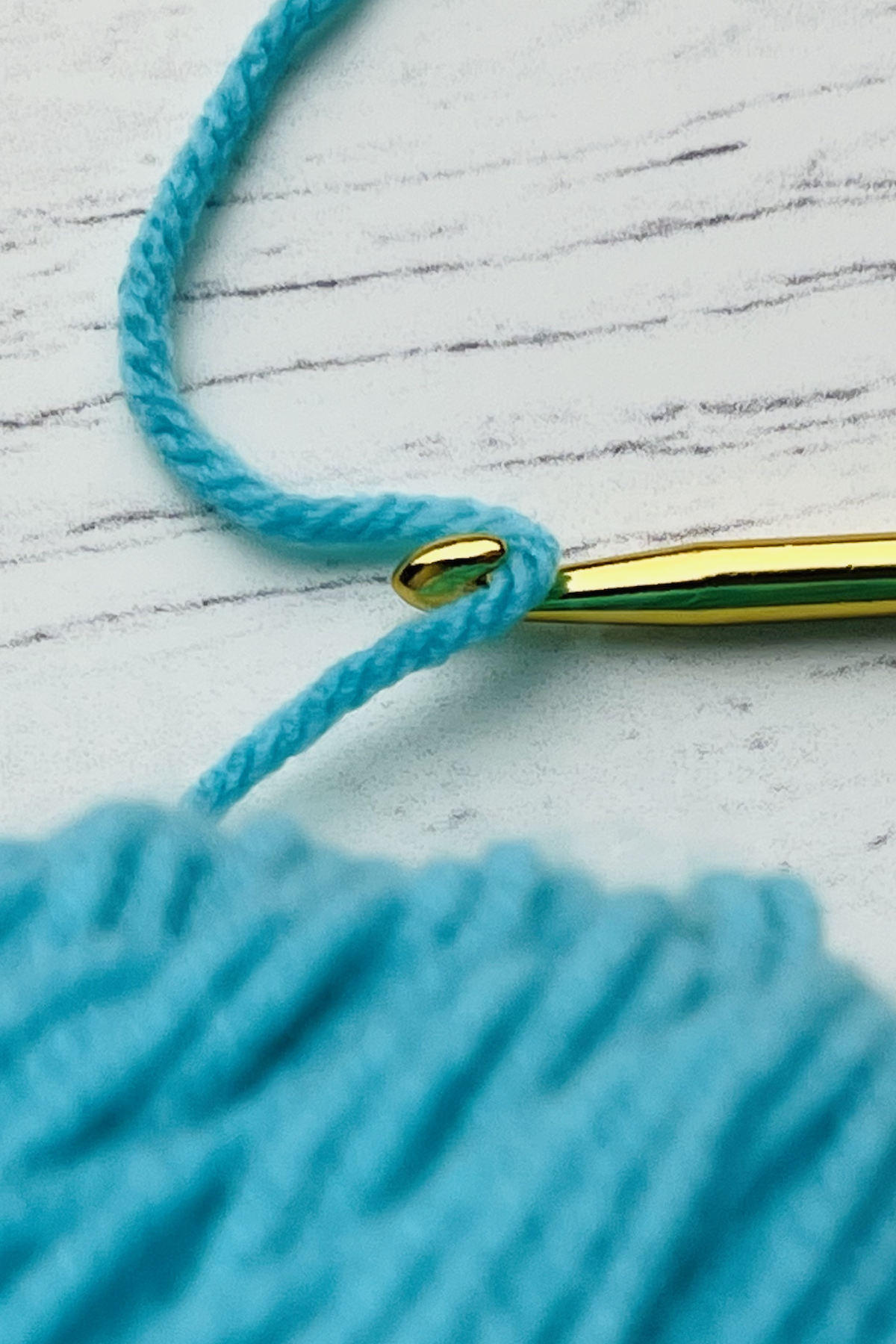 gold crochet hook with bright blue yarn